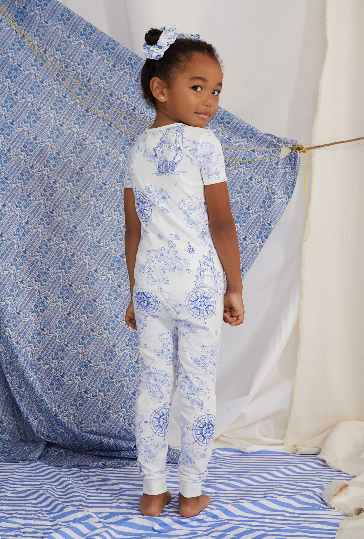 A kid wearing white short sleeve pj set with voyager print.