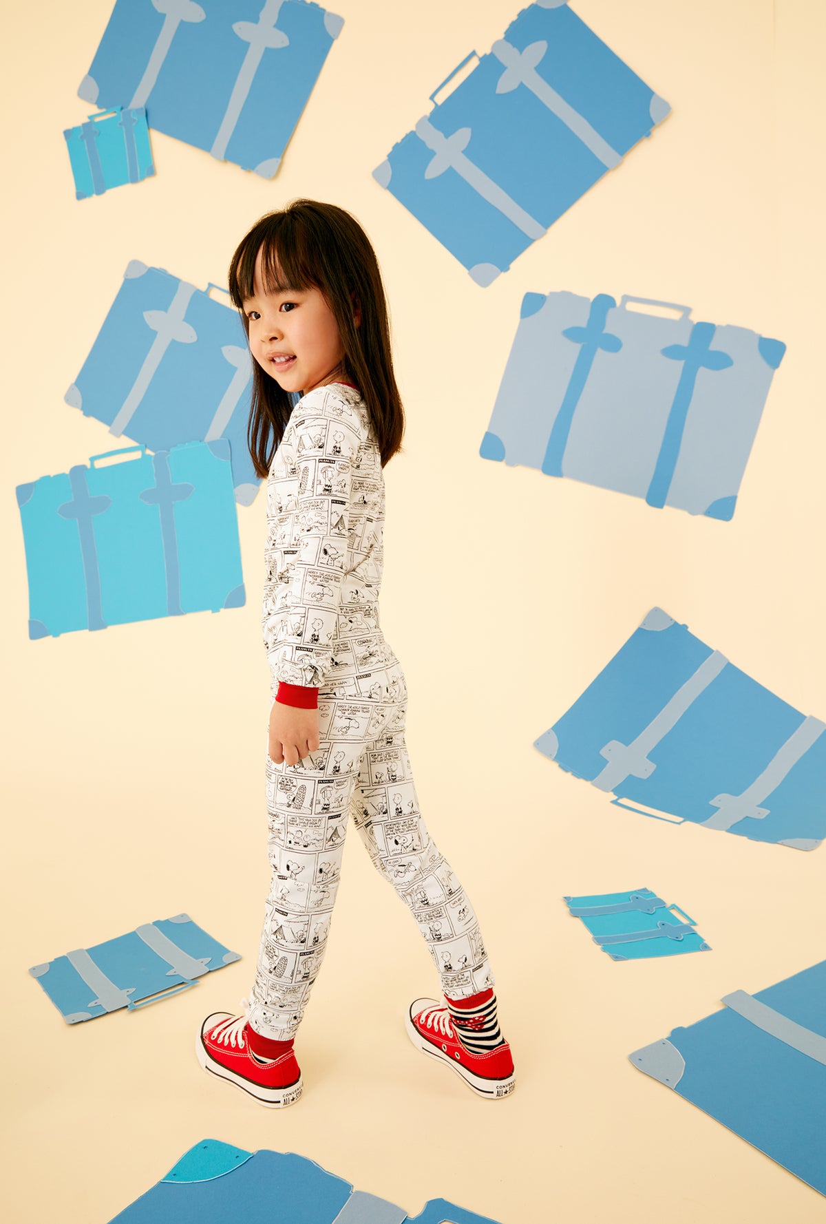  A kid wearing a white long sleeve pajama set with comic strip pattern.