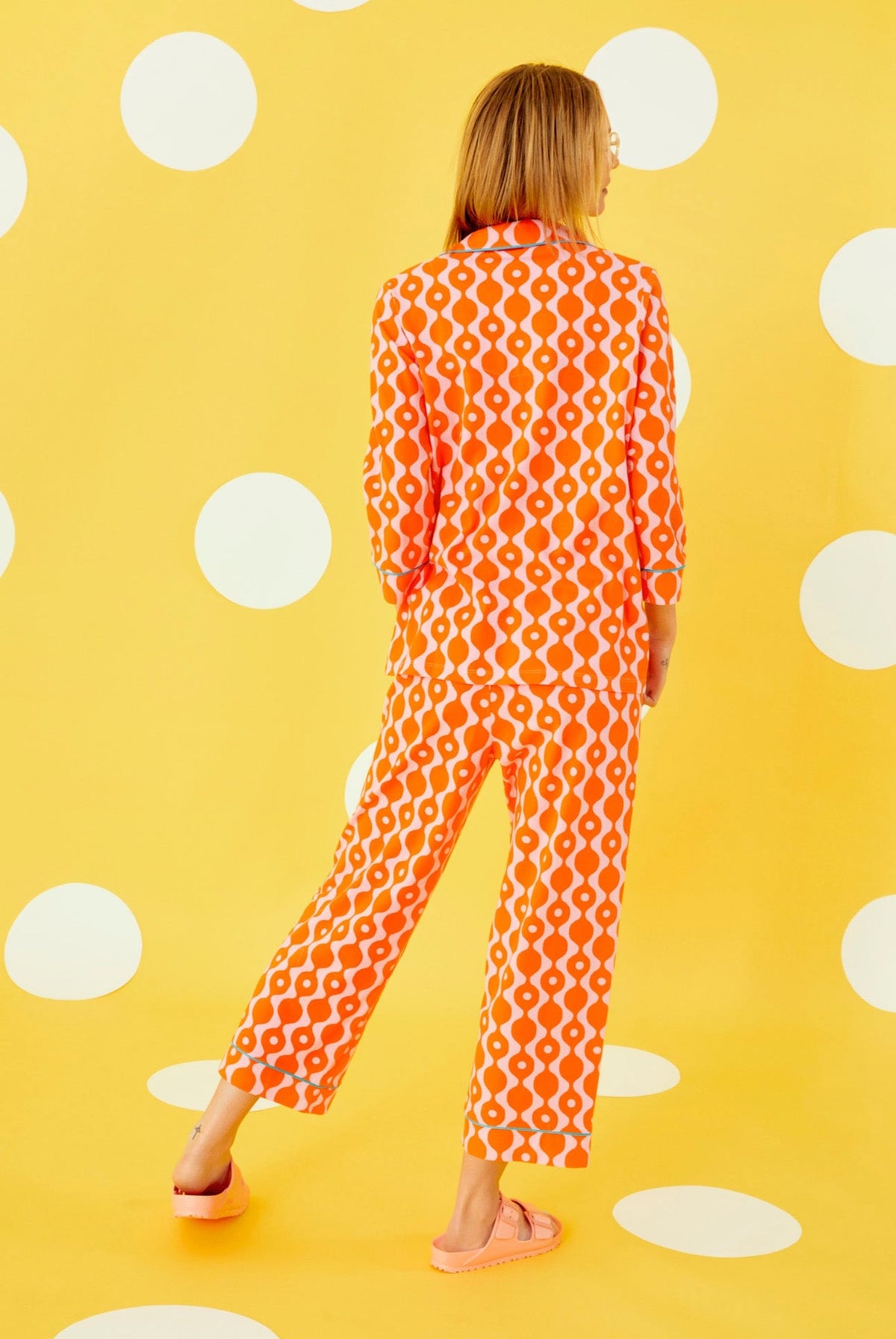 A lady wearing a orange quarter sleeve cropped pajama set with geometric pattern.