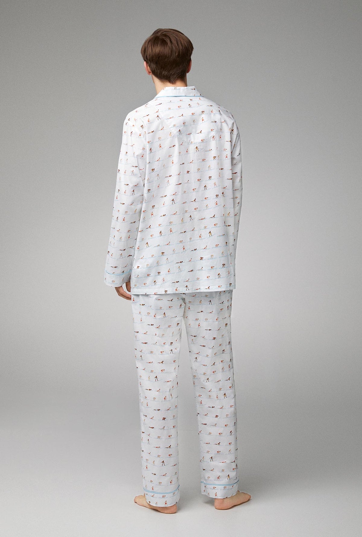 A man wearing white long sleeve classic woven cotton poplin pj set with surf&#39;s up print.