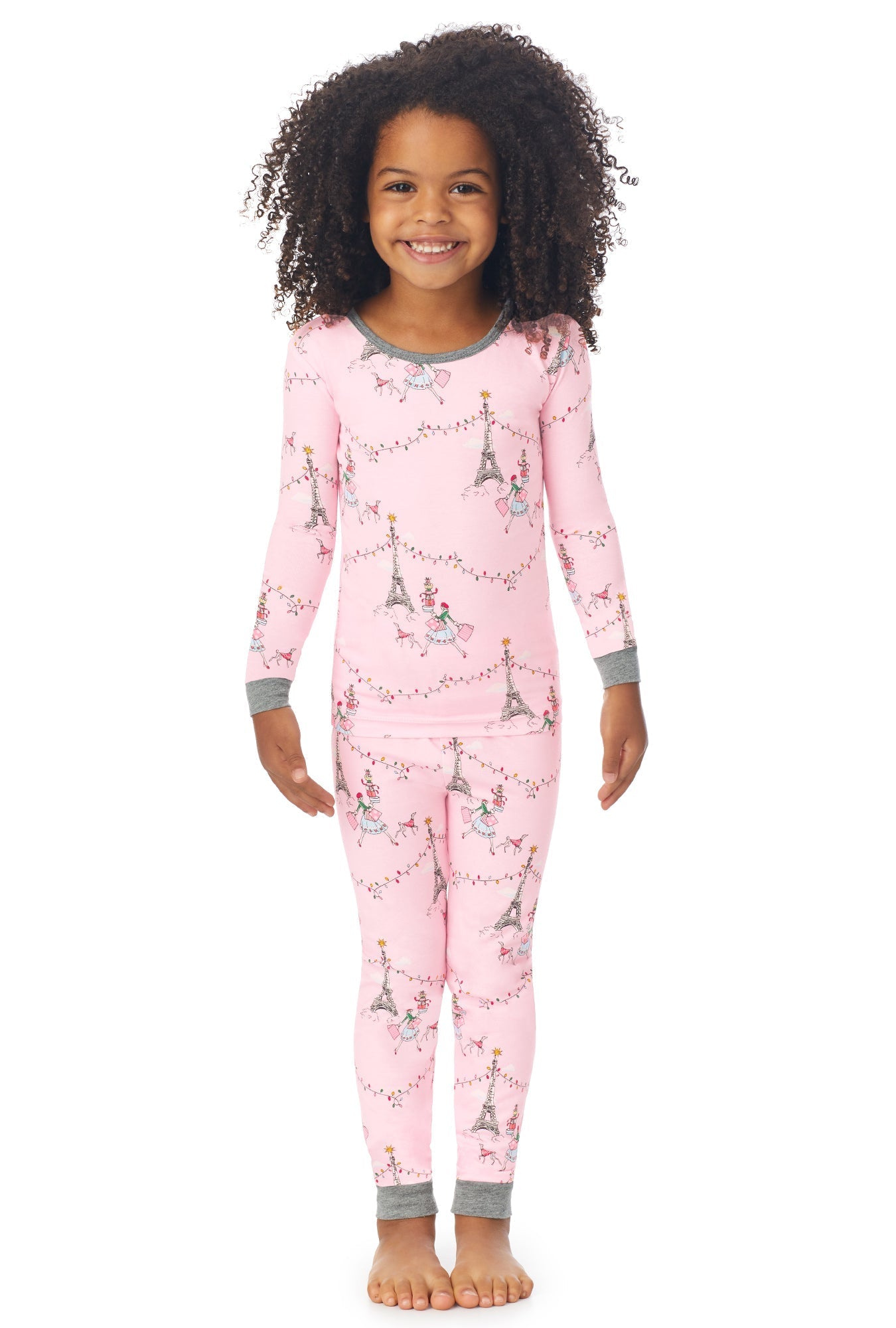 A kid wearing a long sleeve pj set with christmas in paris pattern.