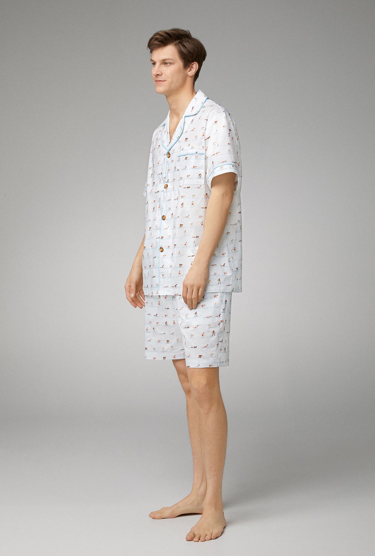 A man wearing white short sleeve notch woven cotton poplin short pj set with surf&#39;s up print.