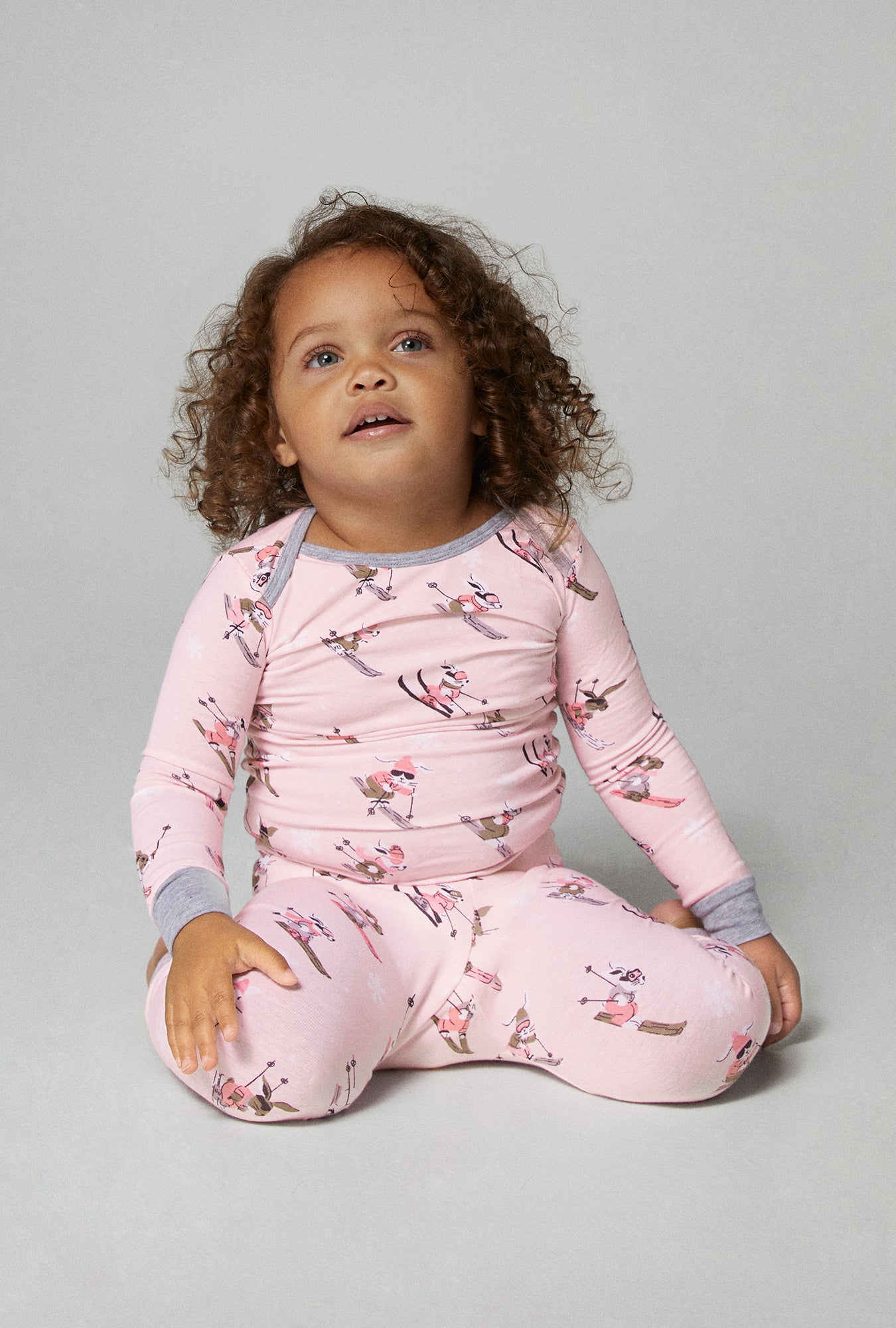 A baby wearing pink long sleeve stretch jersey boo boo pj set with ski bunnies print.