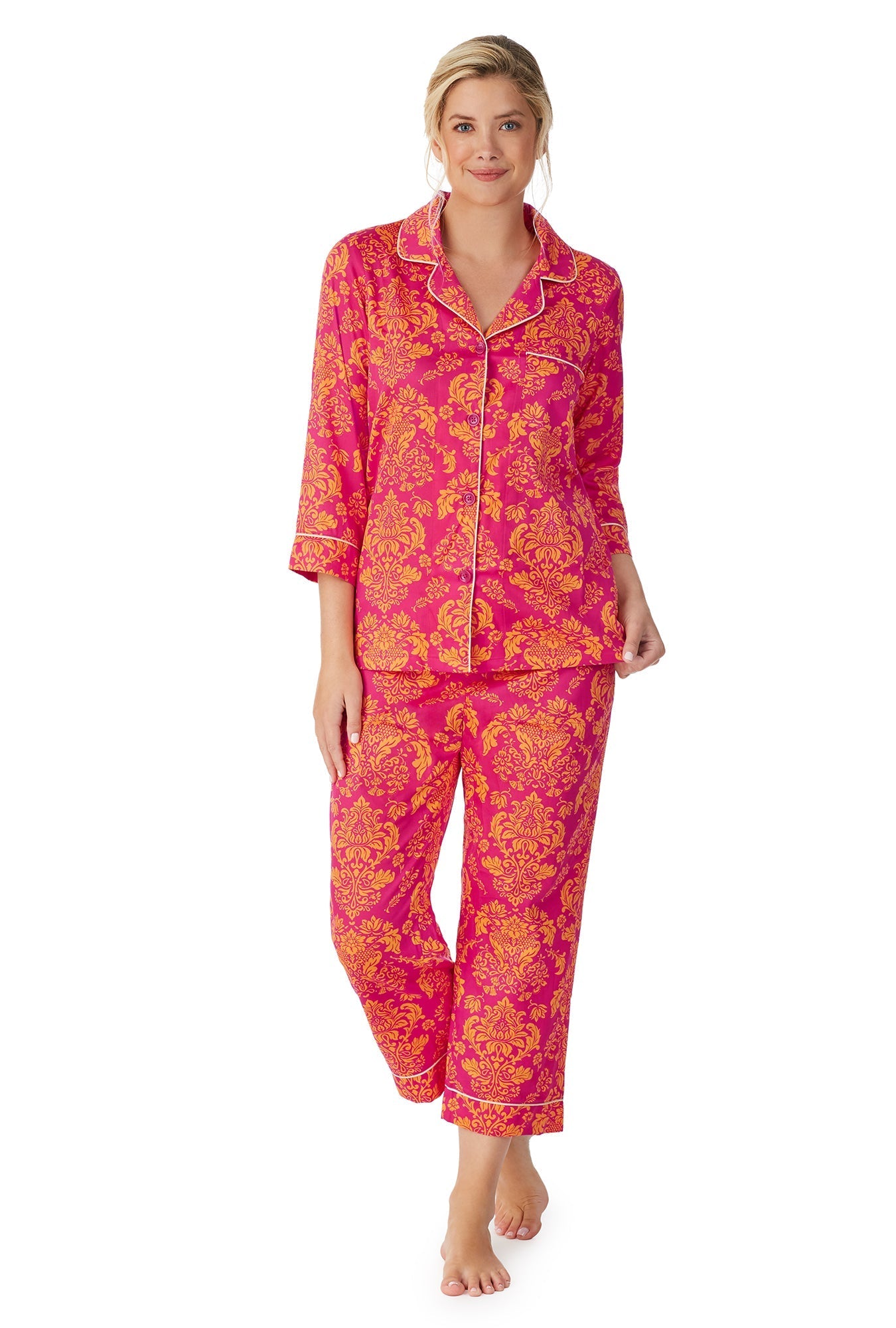 A lady wearing a pink quarter sleeve cropped pj set with orange floral pattern.