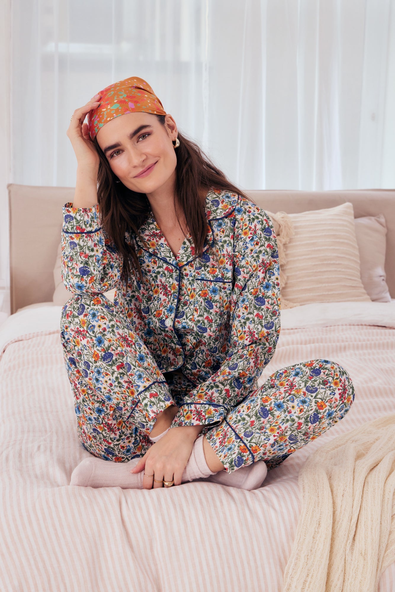 A lady wearing a long sleeve pj set with multicolor floral pattern.