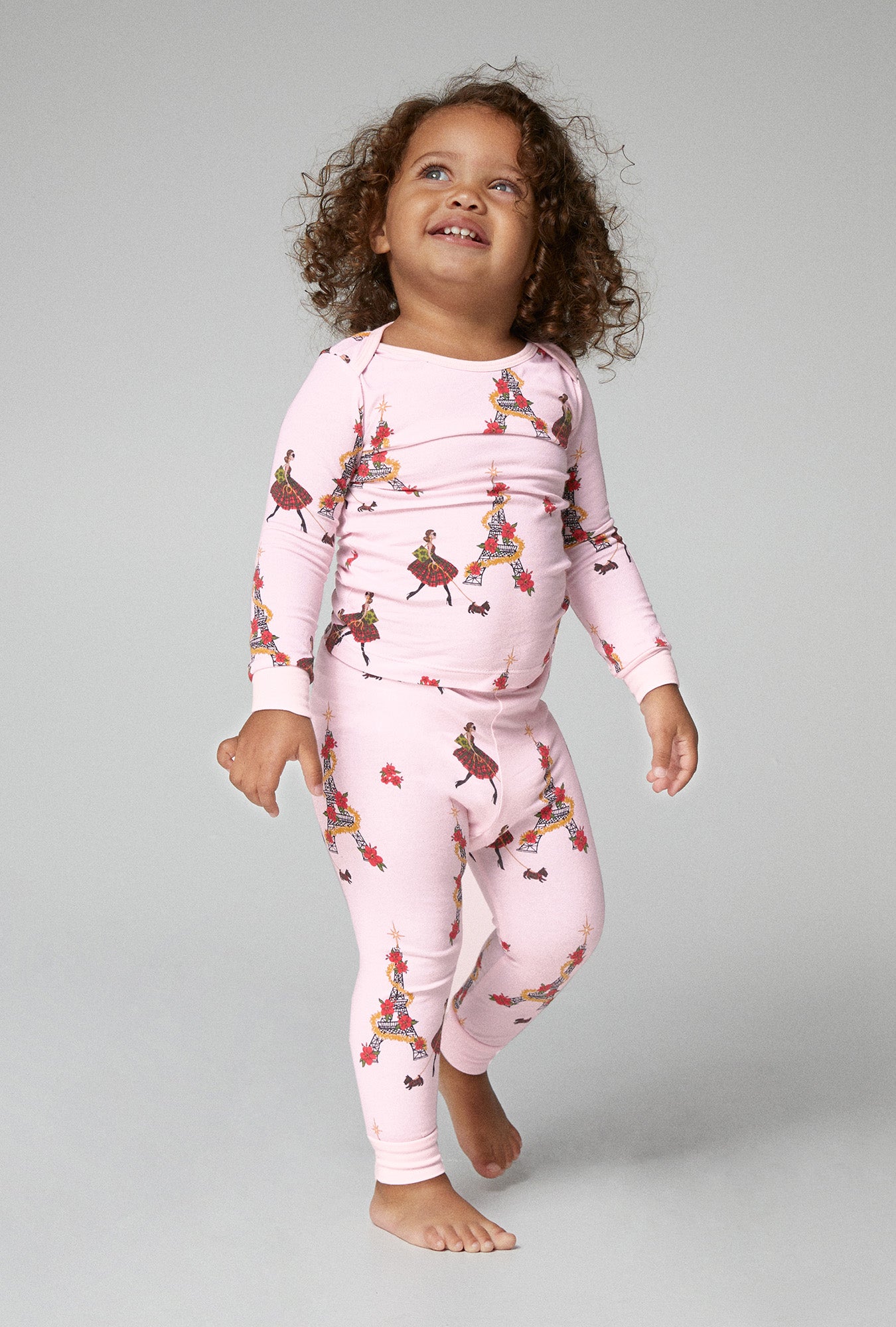 A baby wearing pink long sleeve stretch jersey pj set with christmas chic print.