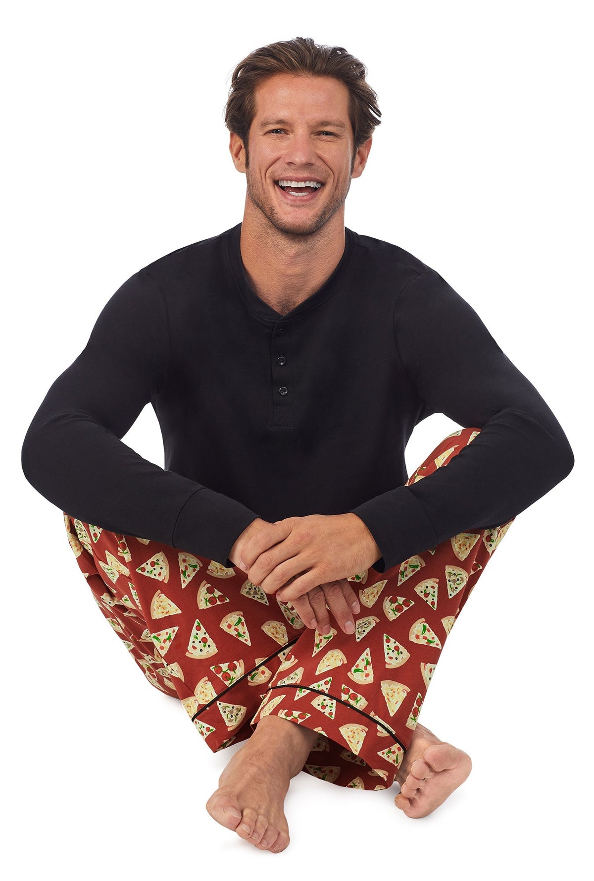A man wearing a black long sleeve jersey and brown long bottom pj set with pizza pattern.
