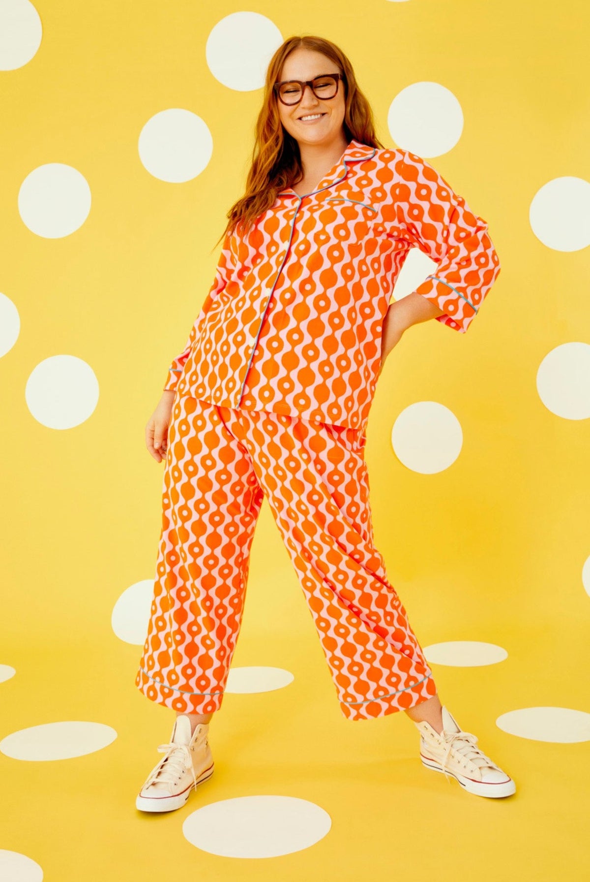 A lady wearing a orange quarter sleeve cropped pajama set plus with geometric pattern.