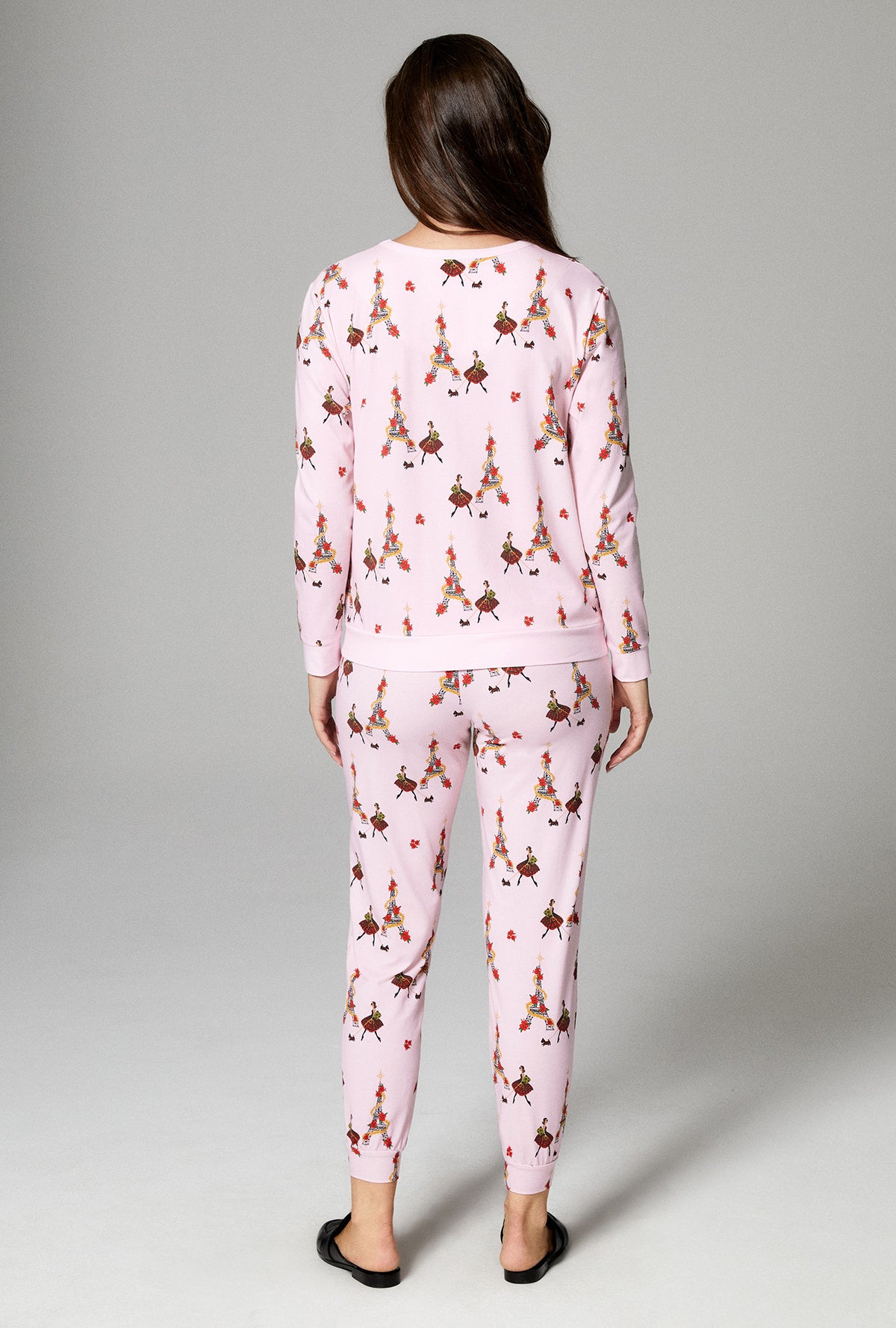 A lady wearing pink long sleeve pullover crew and jogger stretch jersey pj set with christmas chic print.