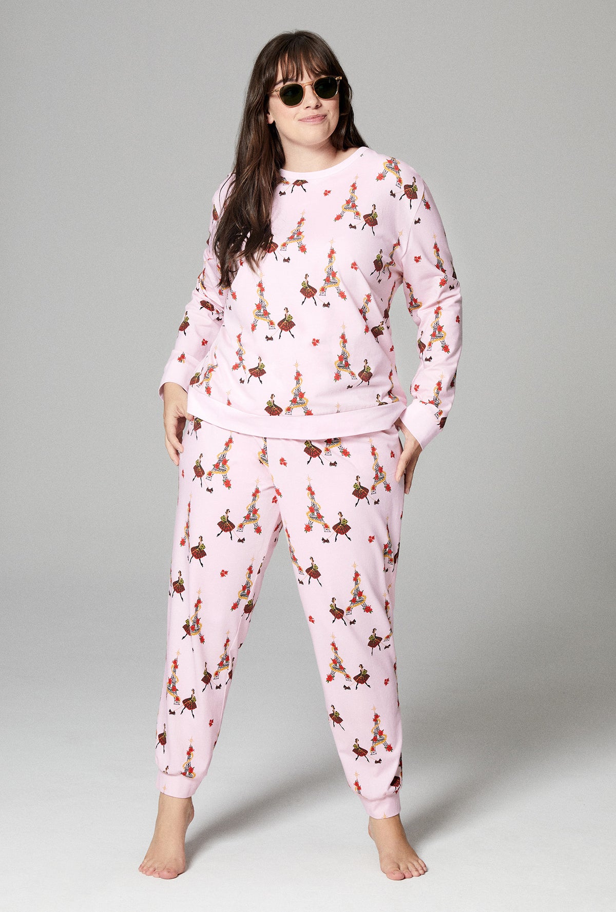 A lady wearing pink long sleeve pullover crew and jogger stretch jersey plus  pj set with christmas chic print.