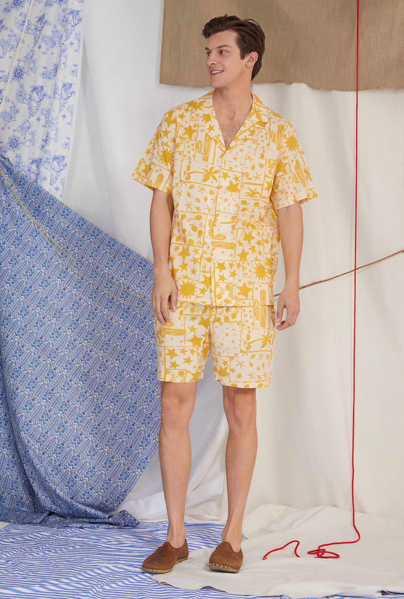 A lady wearing yellow men's short sleeve notch woven cotton poplin boxer pj set with wanderer print.