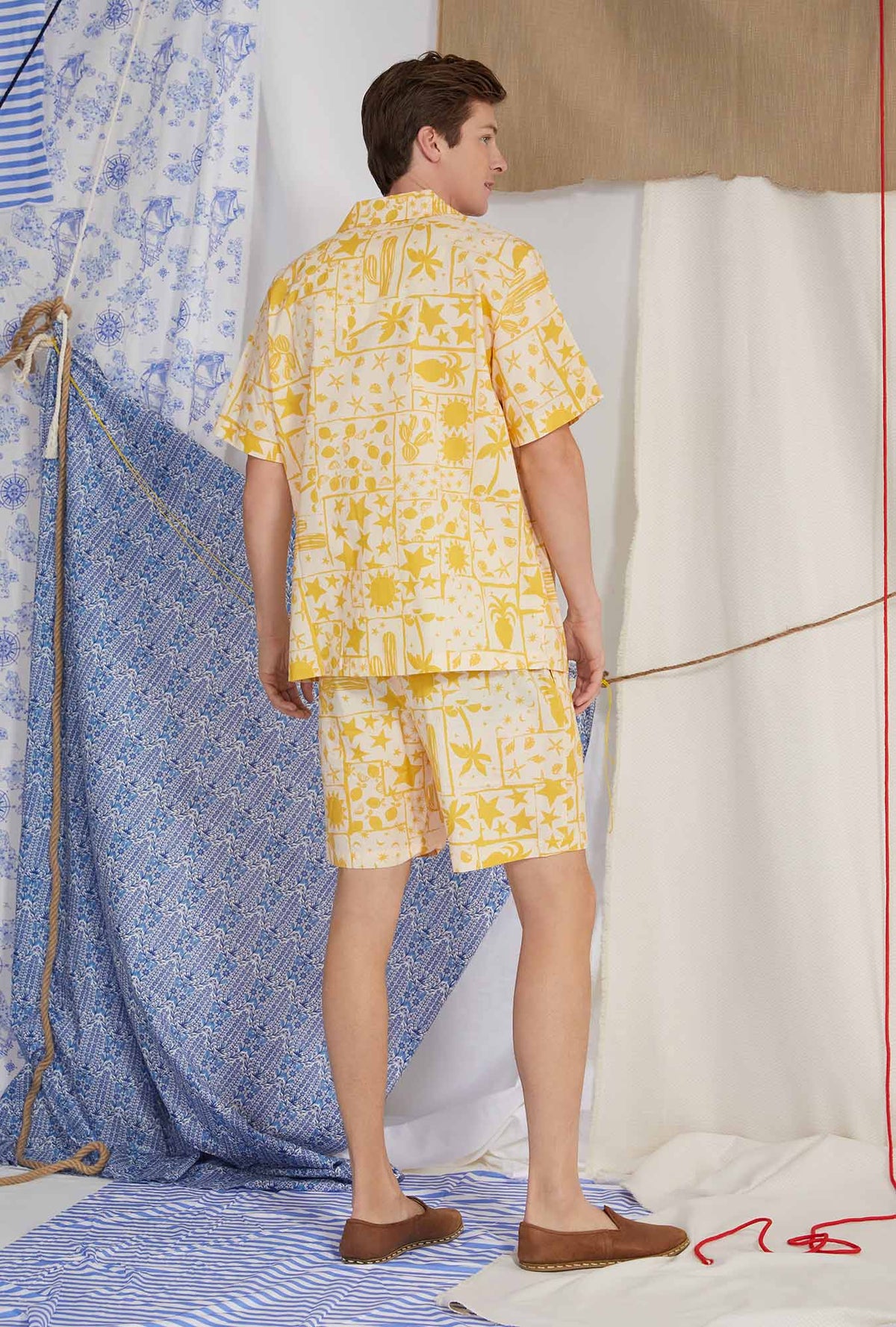 A lady wearing yellow men&#39;s short sleeve notch woven cotton poplin boxer pj set with wanderer print.