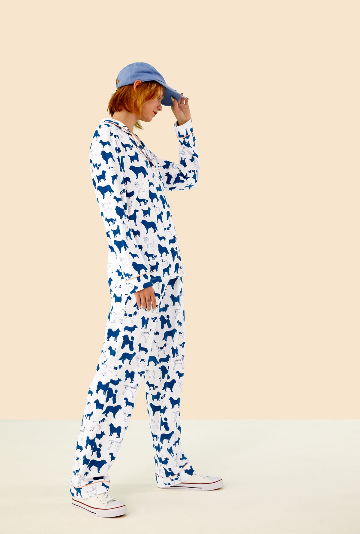 A lady wearing a white long sleeve pajama set with dog pattern.