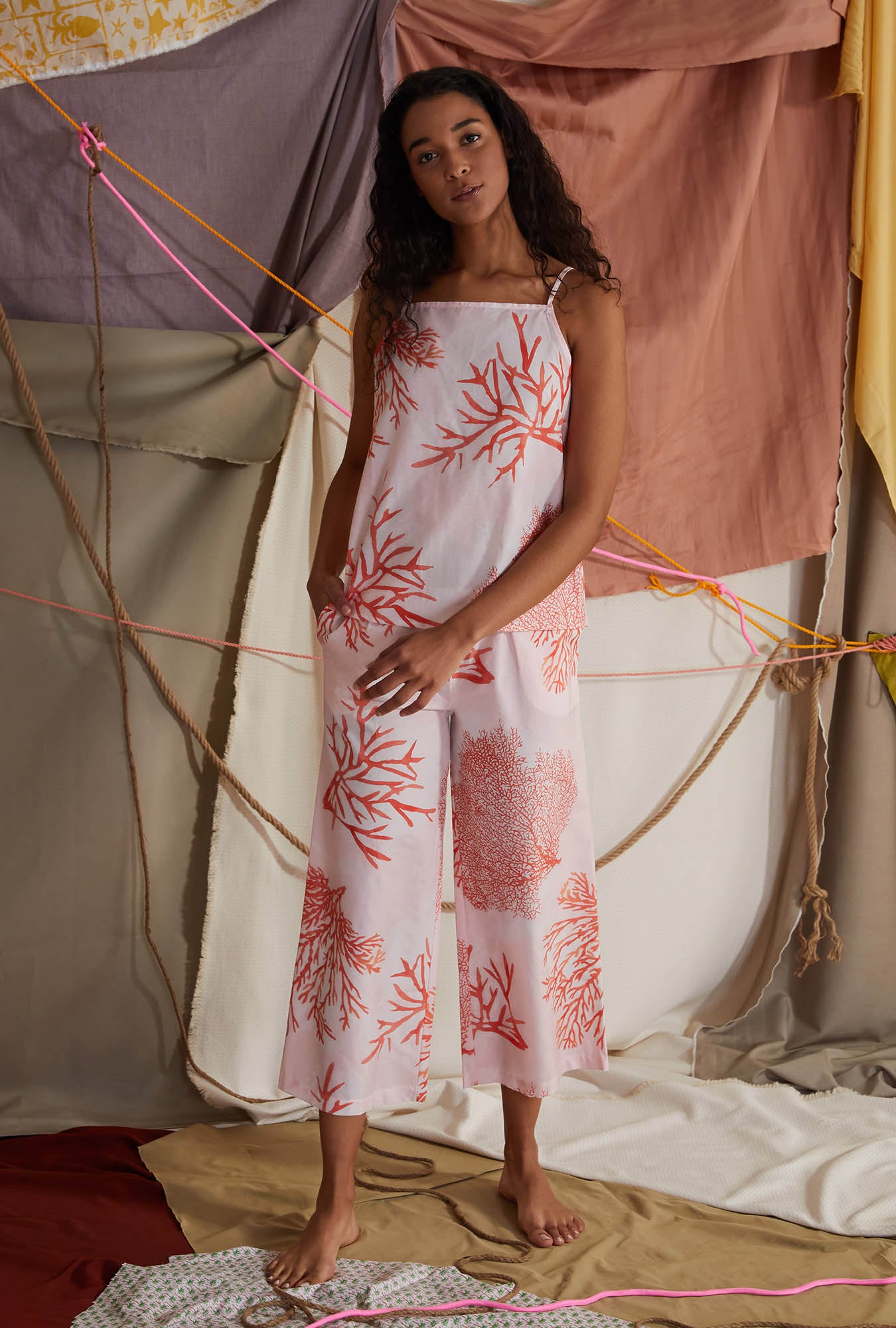 A lady wearing coral sleeveless square neck tank woven cotton silk cropped pj set with sea coral print.