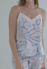 A lady wearing white sleeveless cami silk shorty pj set with octopus garden print.