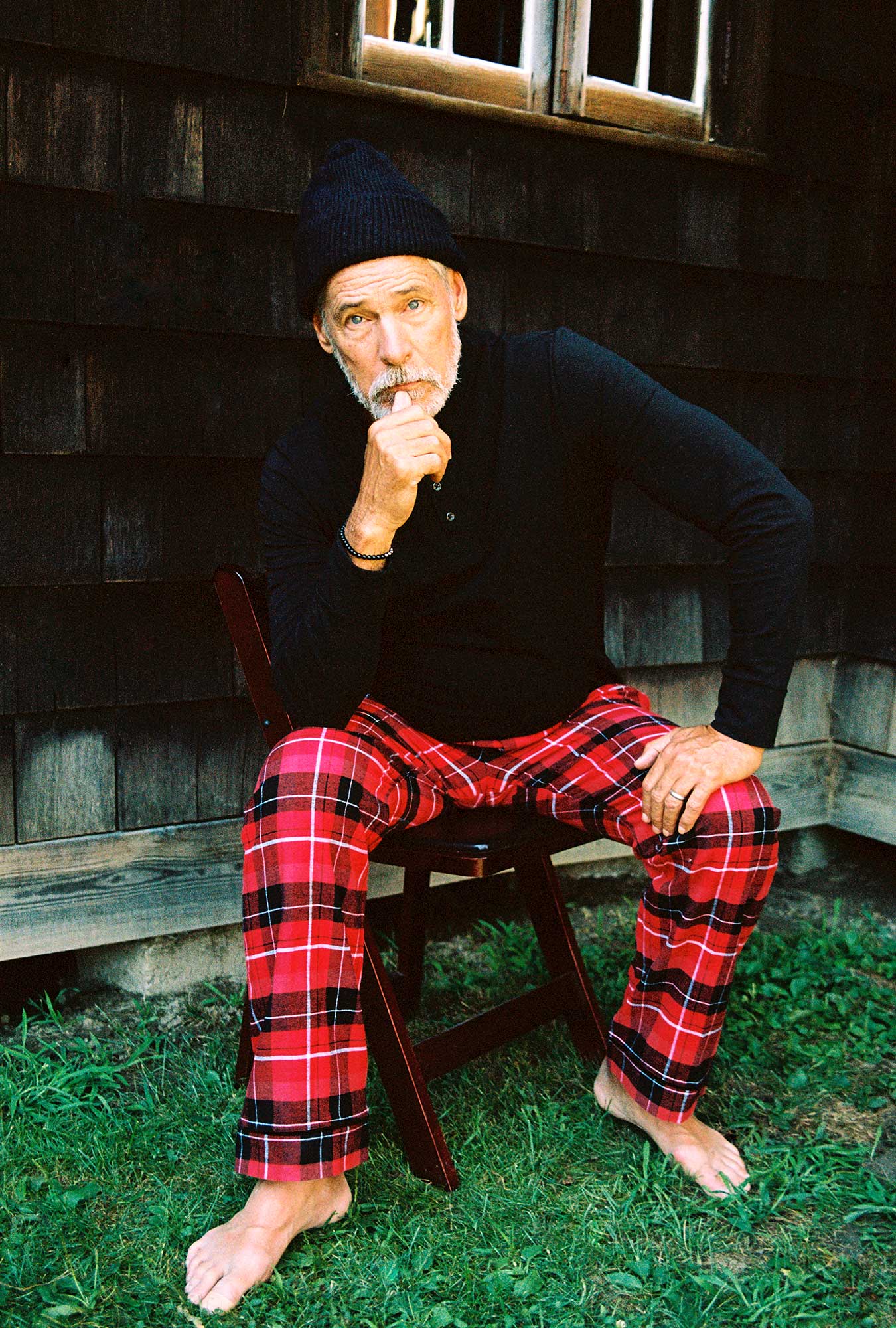 A man wearing red long sleeve henley woven cotton flannel pj set with nicholas plaid print.