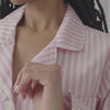 A lady wearing a pink and white stripes long sleeve pj set.